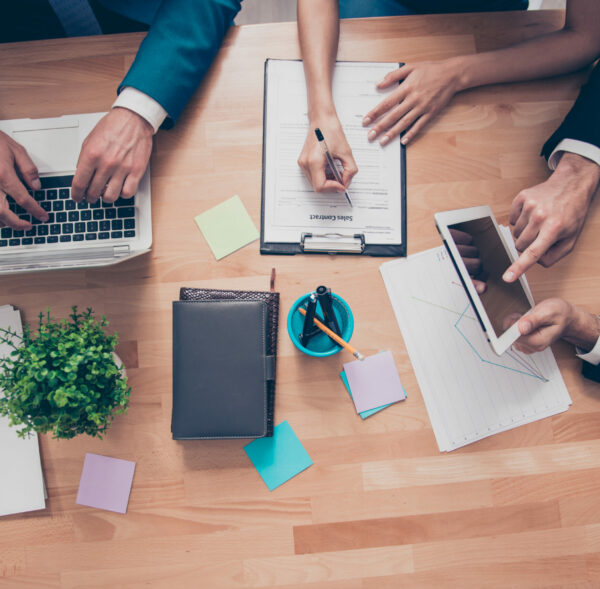Top view of workstation of businesspeople working with laptop, tablet and folder